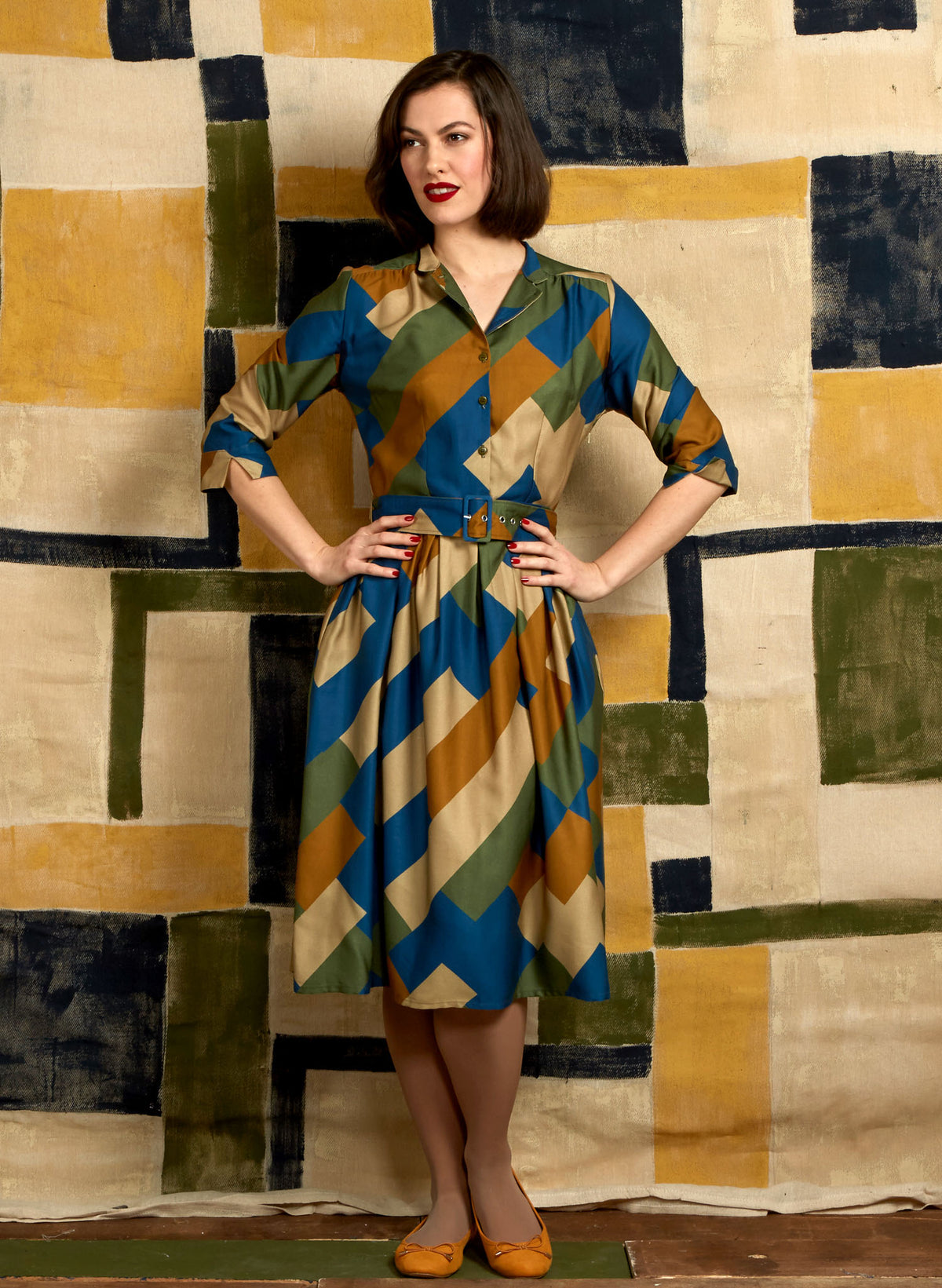 100% Tencel Lyocell green, blue, and gold knee-length belted shirt dress with 3/4 length sleeves, pockets, and a unique, abstract, geometric bauhaus print
