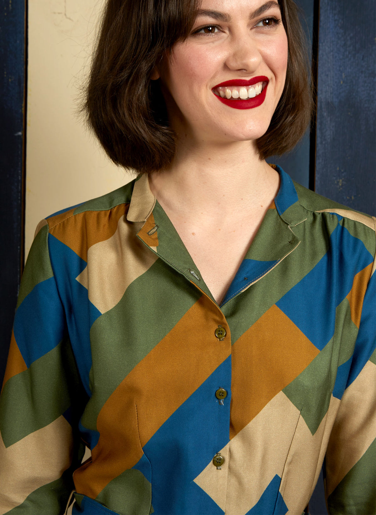 100% Tencel Lyocell green, blue, and gold knee-length belted shirt dress with 3/4 length sleeves, pockets, and a unique, abstract, geometric bauhaus print