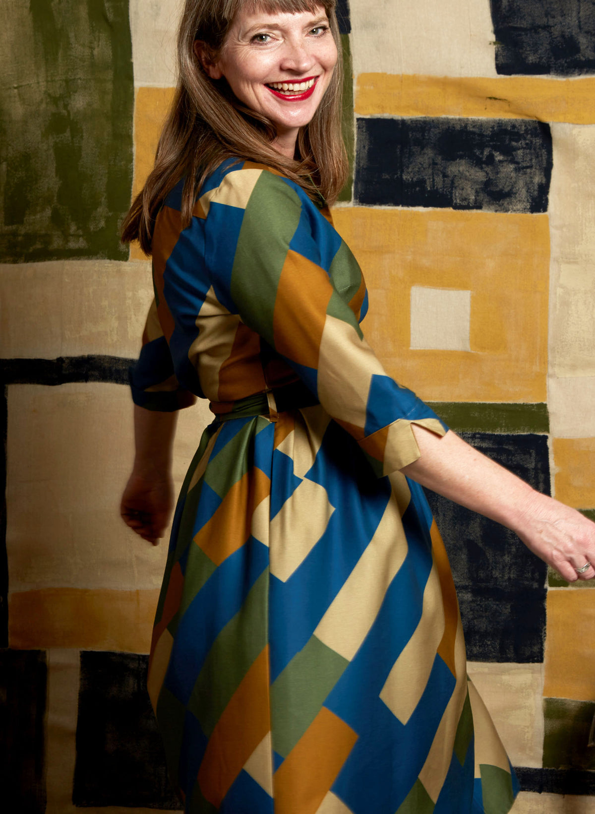 100% Tencel Lyocell green, blue, and gold knee-length belted shirt dress with 3/4 length sleeves, pockets, and a unique, abstract, geometric bauhaus print
