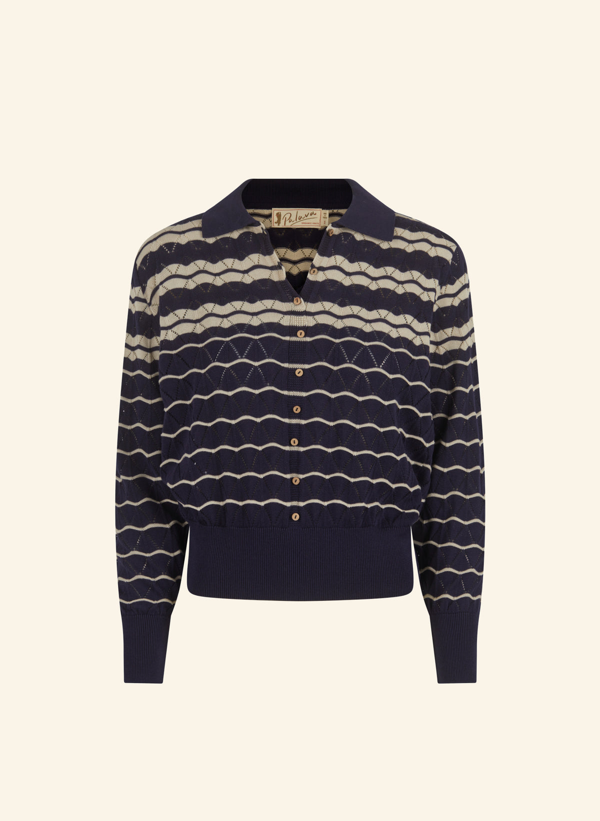 A navy blue knit polo cardigan made from 100% organic cotton with horizontal beige wavy stripes and gold buttons, displayed on a clean cream background.
